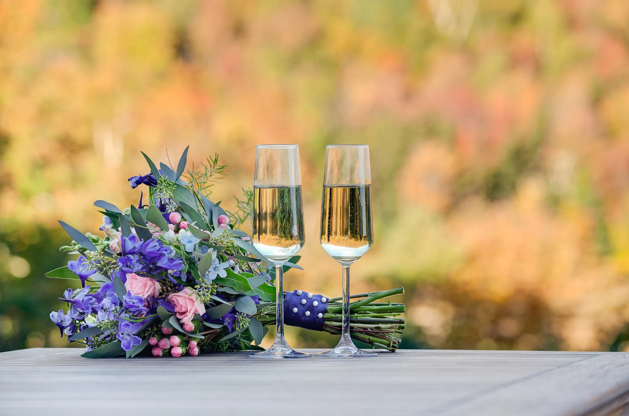 Wedding champagne flutes next to a bouquet of flowers