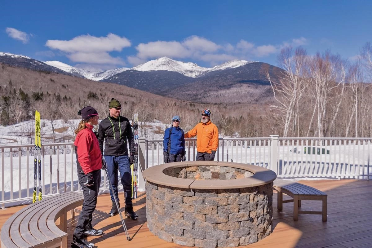 Couples standing in front of the firepit in the winter on the deck of The Glen House