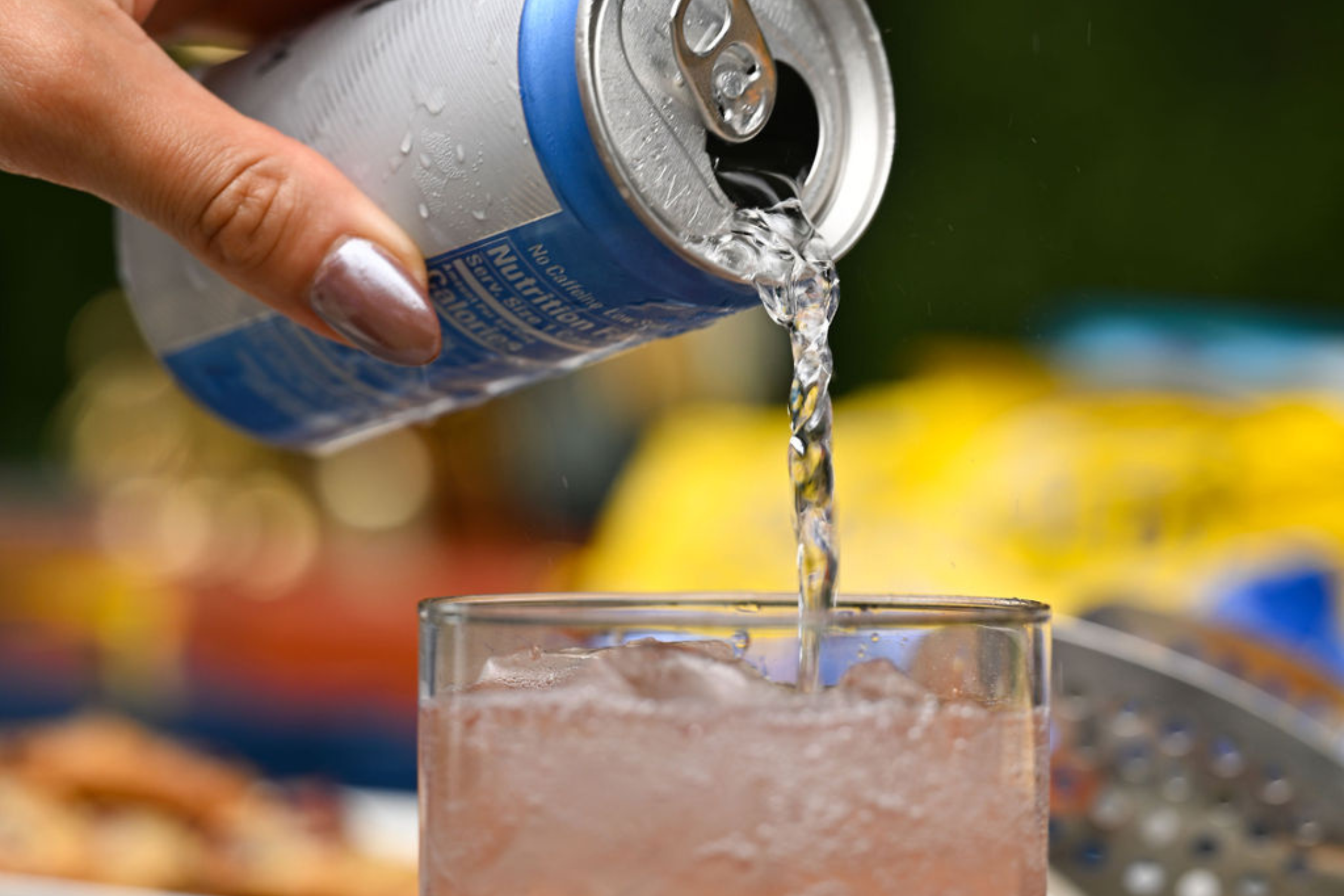 Drink from a can being poured into a glass with ice