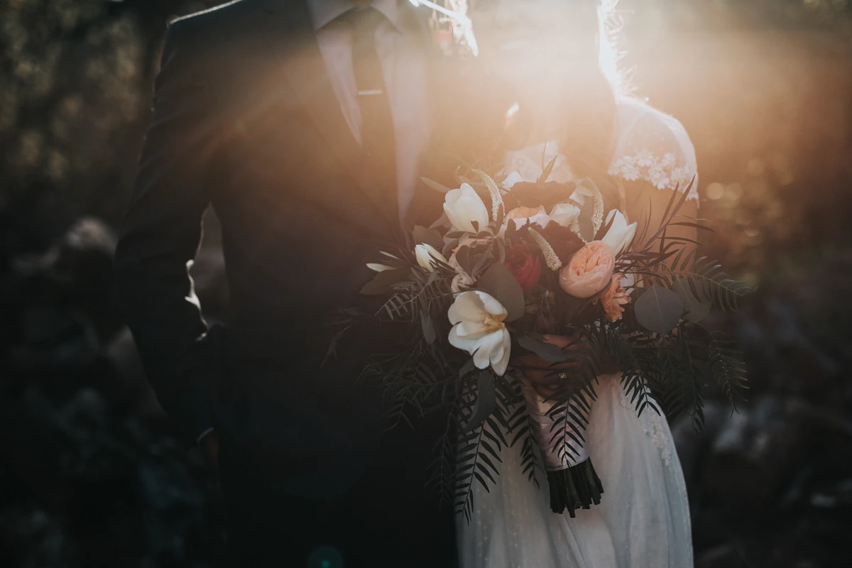 Married couple posing in the forest with a large bouquet