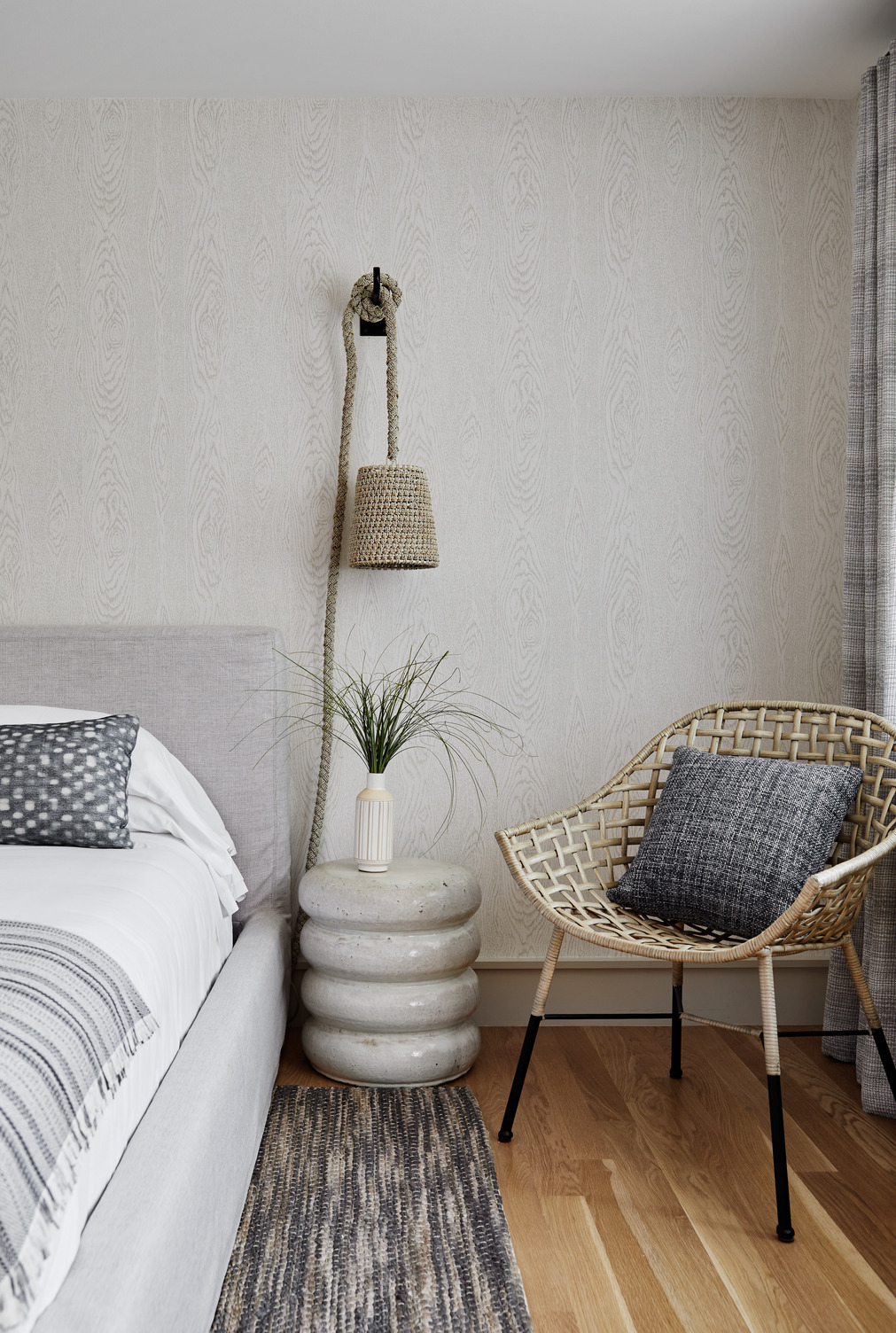 Side table of a guest room with seagrass and a beach styled lamp and chair